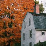 beautiful white wood home amid trees with exploding orange fall colours