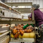 woman works on production line cleaning sweet potatoes