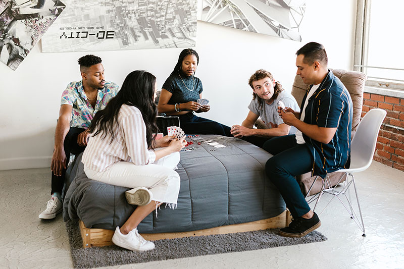 young university students playing cards on a bed in a dorm